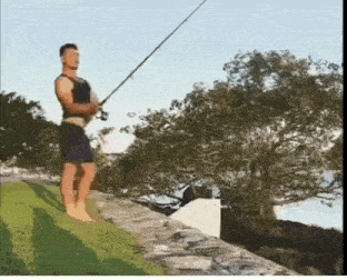 a man is holding a fishing rod while standing on a rock wall next to a body of water .