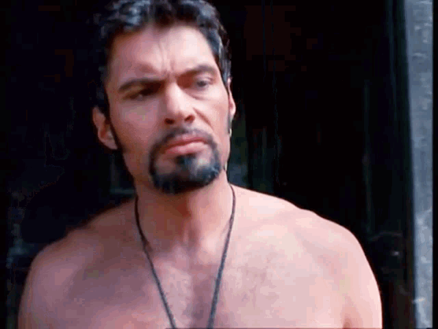 a shirtless man with a beard is wearing a necklace around his neck