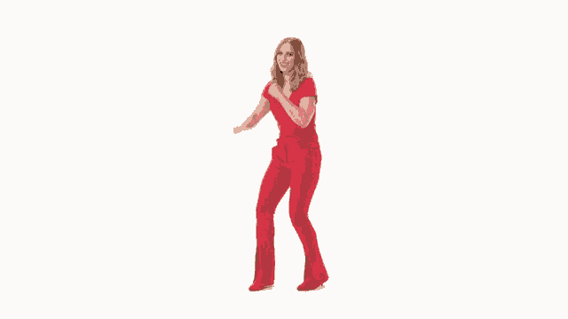 a woman in red pants and a red shirt is standing with her fist in the air