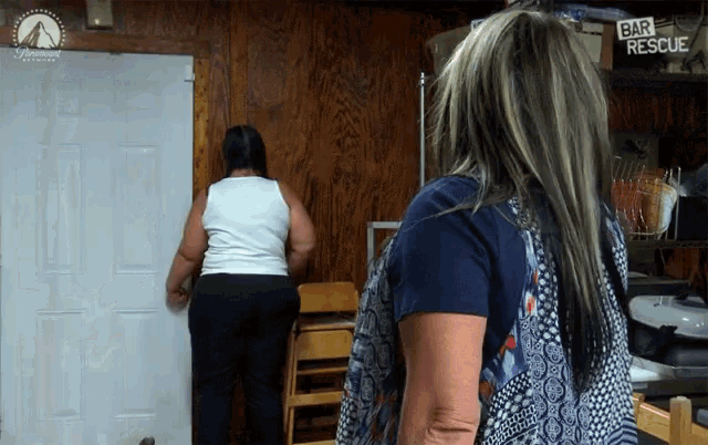 two women standing in front of a door with a sign that says bar rescue
