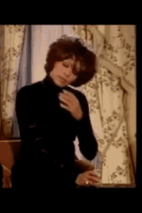 a woman in a black turtleneck sweater is standing in front of a window