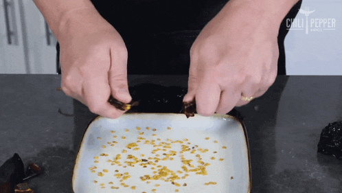 a person 's hands are reaching into a white plate that says chili peppers