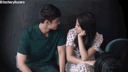 a man and a woman are sitting next to each other on a couch and looking at each other .