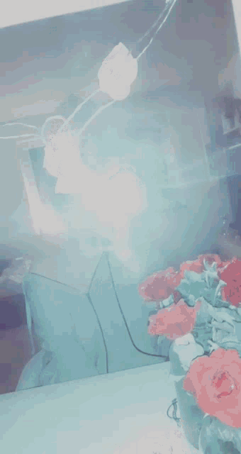 a reflection of a person in a mirror with red roses in front of them
