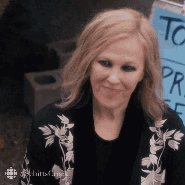 a woman is smiling in front of a sign that says to pray