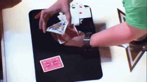 a person in a green shirt is playing a game of cards with a pink card that says e on it