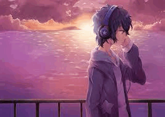 a young boy wearing headphones is standing on a balcony overlooking the ocean .