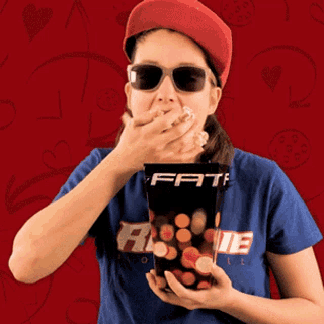 a woman wearing sunglasses and a hat is eating from a box that says fate on it