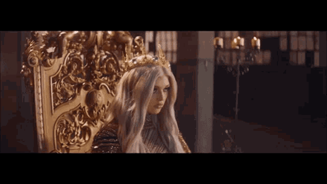 a woman wearing a crown sits on a gold throne