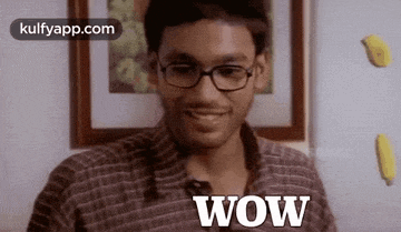 a man wearing glasses and a plaid shirt is smiling and says wow .