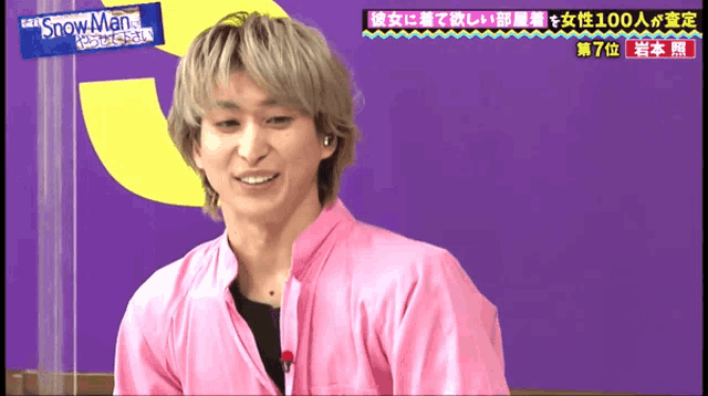 a man in a pink shirt is smiling in front of a snowman sign