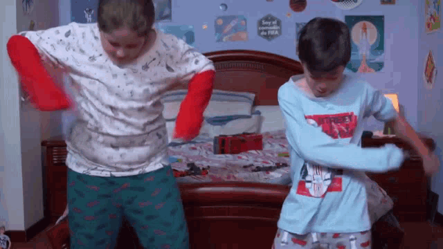 two boys are dancing in front of a bed with a sign that says " soy el único en la fifa "