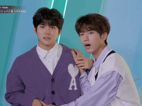 two young men are standing next to each other and one has a heart on his sweater