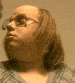 a woman with long hair and glasses is looking at herself in a mirror .