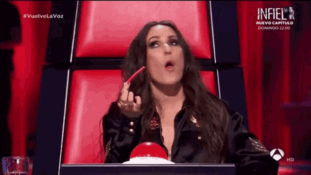a woman sitting in a chair with a red button in front of her that says infiel on it