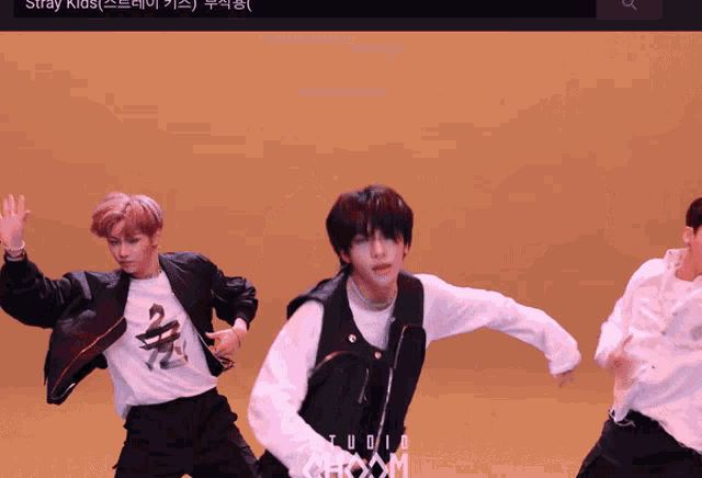 a group of young men are dancing in front of a yellow background that says studio