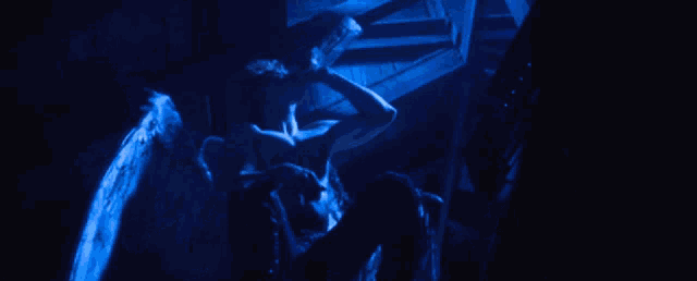 a man with blue wings is holding a snake in his hands
