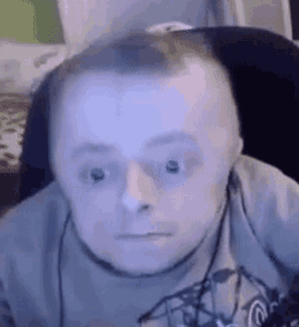 a man with down syndrome is wearing headphones and making a funny face while sitting in a chair .