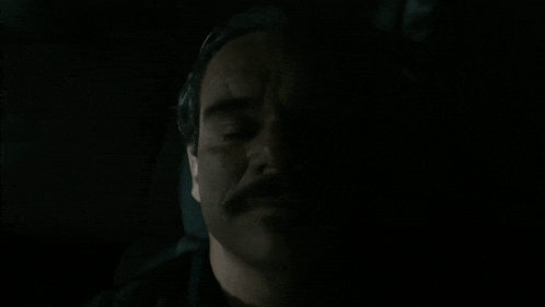 a close up of a man 's face in the dark with his eyes closed .