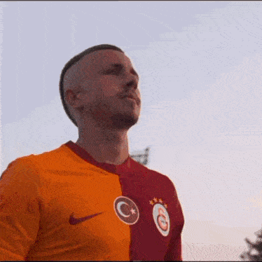 a man wearing an orange and red nike shirt with a c on it