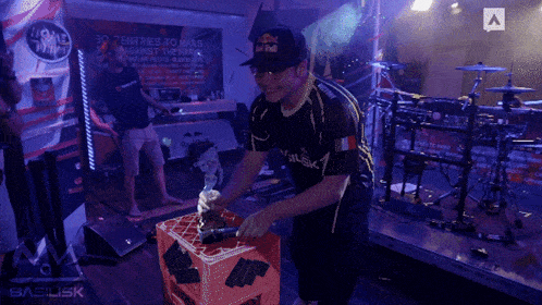 a man wearing a red bull hat is standing in front of a sign that says 30 entries to make against the wall