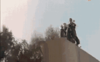 a group of people are standing on top of a cliff .