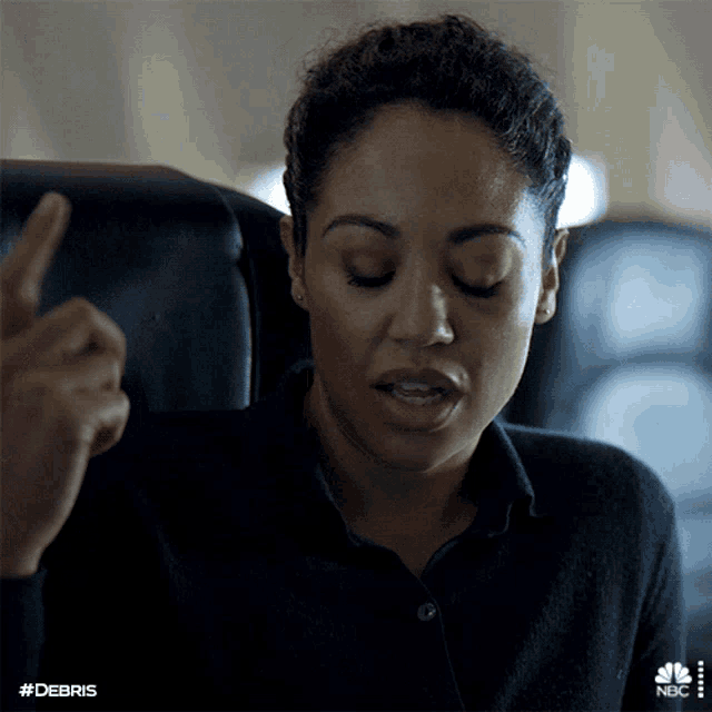a woman sits in a chair with her eyes closed and a hand pointing at her with the hashtag #debris
