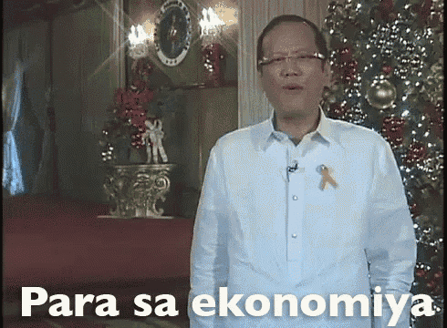a man in a white shirt is standing in front of a christmas tree with the words para sa ekonomiya below him