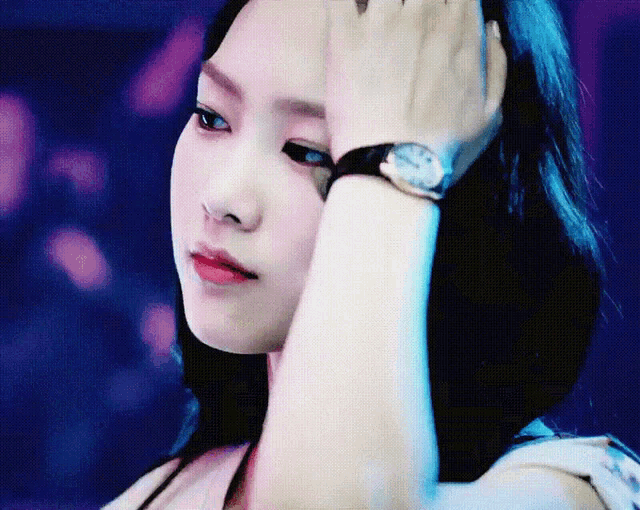 a woman wearing a watch holds her hand to her head