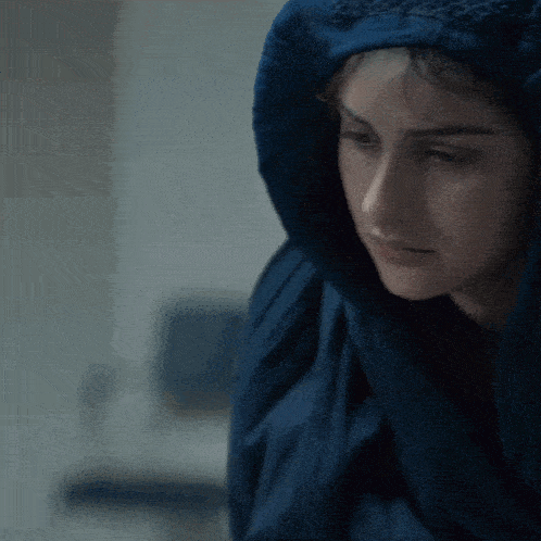 a woman wrapped in a blue blanket looks down