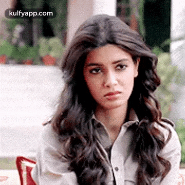 a woman with long hair is sitting on a couch with a sad look on her face .