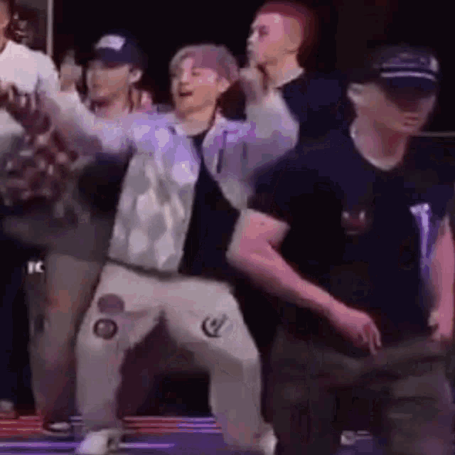 a group of men are dancing together on a stage in a dark room .