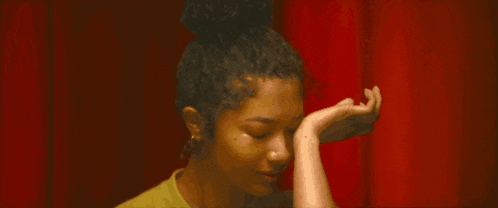a woman in a yellow shirt is covering her face with her hand .