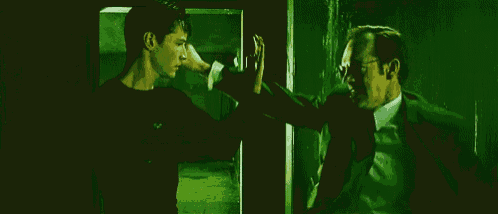 a man in a suit and tie is standing next to another man in a dark room .