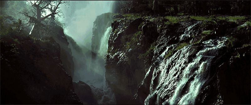 a waterfall is surrounded by trees and rocks in a dark forest