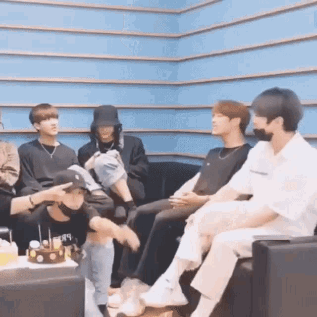 a group of people are sitting on a couch in a room with a cake in the middle .