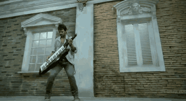 a man is playing a keyboard in front of a brick building