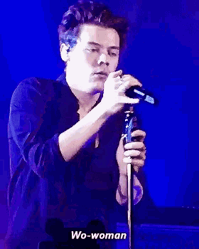a man is singing into a microphone on a stage in front of a mickey mouse .