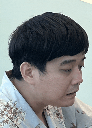 a man wearing a shirt with flowers on it looks down