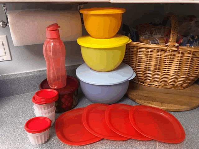 a stack of bowls and plates sit on a counter next to a basket