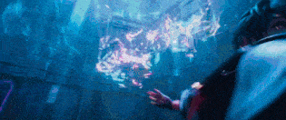 a man is standing in a dark room with a glowing object coming out of the wall .