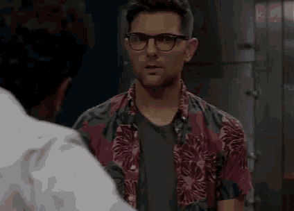 a man in a colorful shirt is talking to another man in a white shirt .