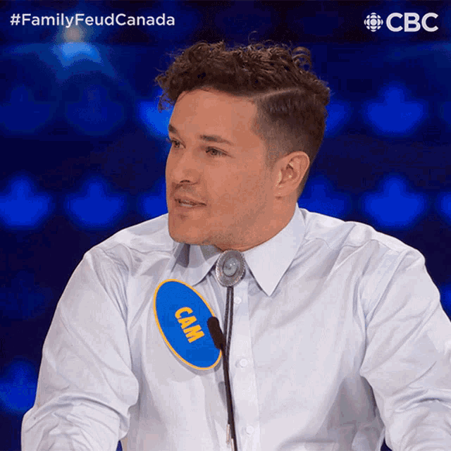 a man in a white shirt has a blue circle with the word cam on it