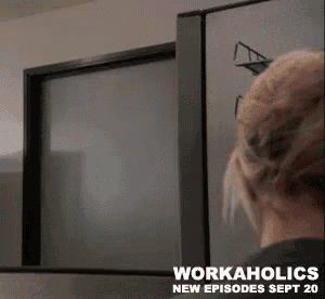 a woman is standing in front of a television with the words workaholics on the bottom .