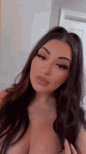 a woman with long dark hair is taking a selfie with her eyes closed .