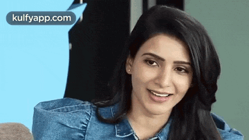 a close up of a woman wearing a blue denim shirt and smiling .