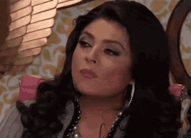 a woman wearing a necklace and earrings is making a funny face