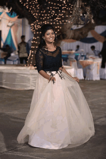 a woman wearing a black top and a white skirt is smiling