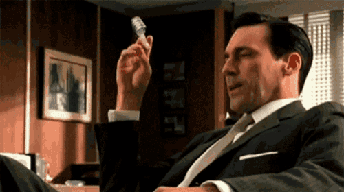 a man in a suit and tie holds a light bulb in his hand