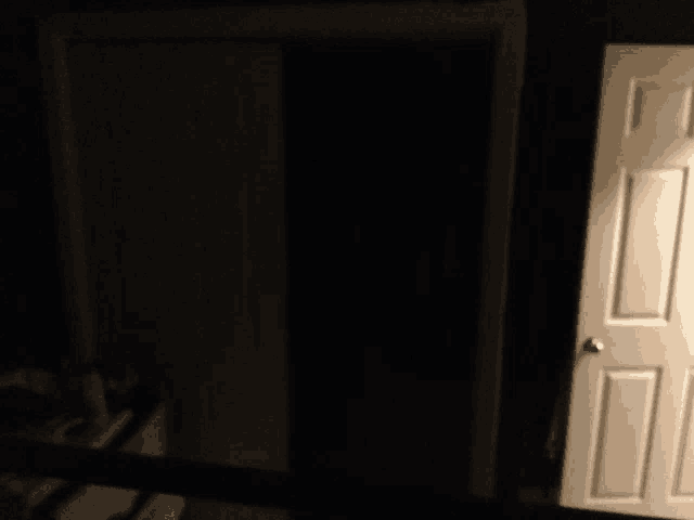 a white door in a dark room with a black curtain behind it